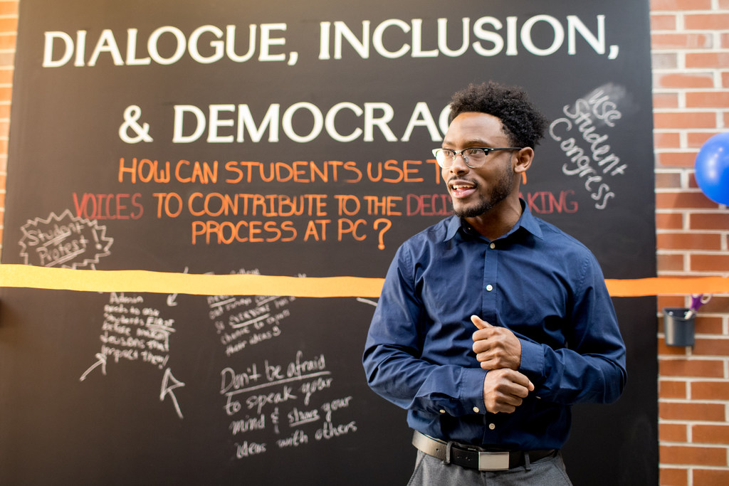 student speaking in front of chalk board