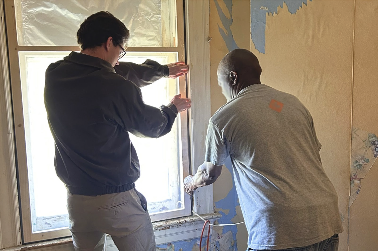 Elliot assists a St. Louis resident with installing a window-insulating insert.