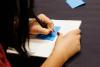 student writing on a post-it